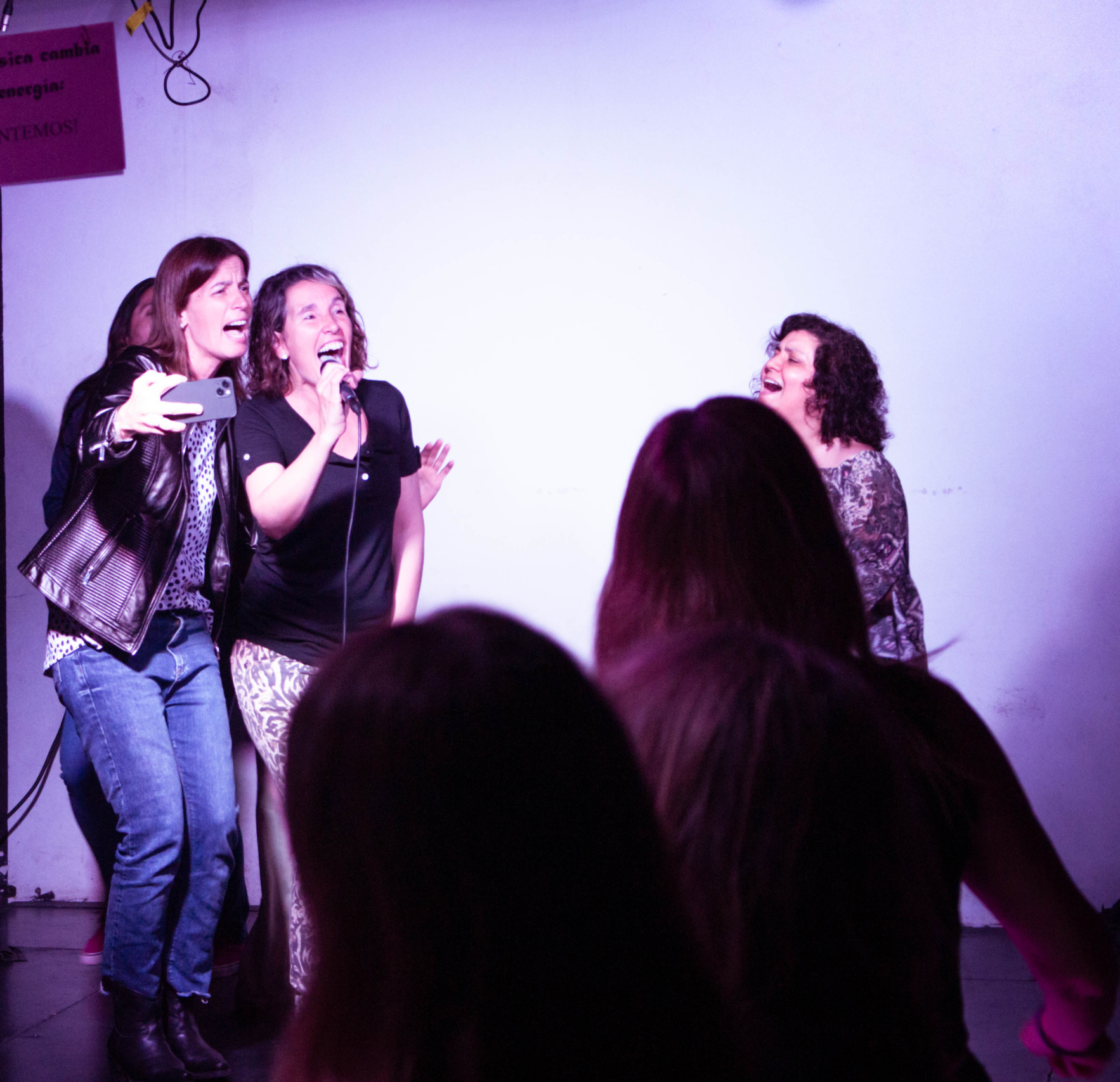 Tres mujeres cantando con micrófono en un escenario