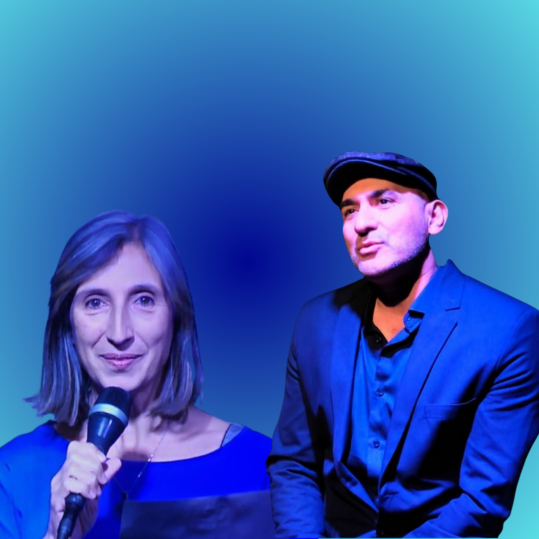 En la foto se observan dos personas. Adelante en primer plano una mujer con un micrófono en la mano y atrás un hombre con traje y boina. Los dos vestidos elegantes. El fondo es azul